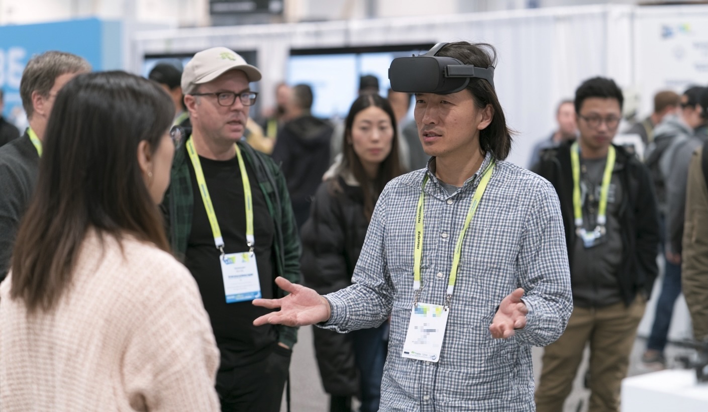 Un visiteur en casque de réalité virtuelle échange avec une personne sur le salon